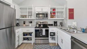 Una cocina moderna con armarios blancos, electrodomésticos de acero inoxidable y un horno empotrado.