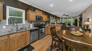 Una cocina moderna con armarios de madera, electrodomésticos de acero inoxidable y un comedor con mesa y sillas de madera.