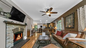 Una sala de estar con chimenea, sofá de cuero y ventilador de techo.