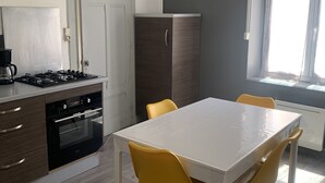 A modern kitchen with a white table, yellow chairs, a built-in oven, and a refrigerator. - Gîte des Serves apparently 40m2 Chavanay 5 people (Chavanay)