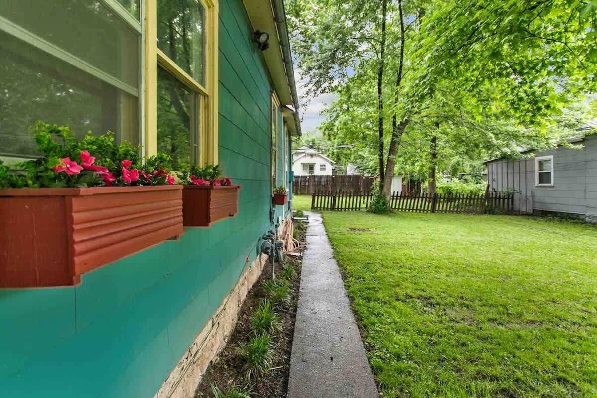 A house with a green exterior, a wooden fence, and a grassy yard.