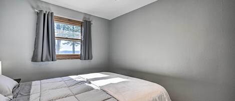 Un dormitorio con cama, ventilador de techo y ventana con cortinas.