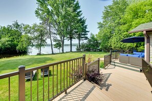 Um deck com vista para um lago, cercado por árvores e um gramado.