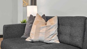Un sofá gris con cojines estampados en una habitación con tonos neutros.