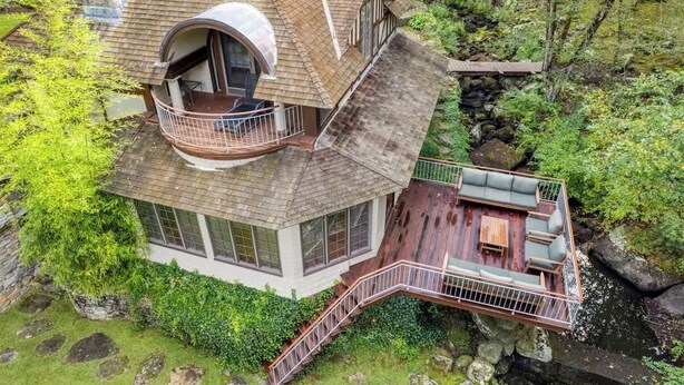Une maison dotée d’un balcon circulaire, d’une terrasse avec des meubles d’extérieur et d’un mur en pierre.