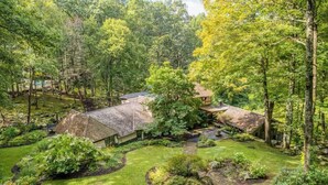 Une maison entourée d’une végétation luxuriante et dotée d’un jardin bien entretenu, avec un chemin en pierre.