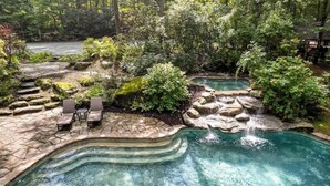 Un site de sources chaudes avec une piscine aux eaux cristallines, des marches en pierre et des chaises longues.