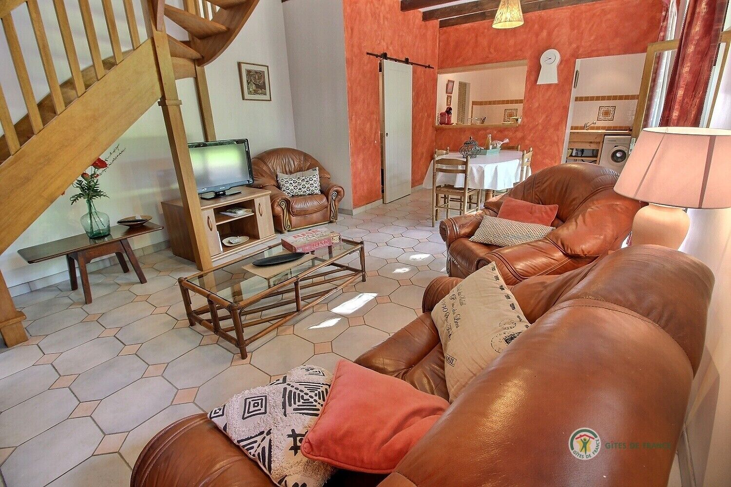 Una sala de estar con un sofá, una mesa de centro, un televisor y una escalera.