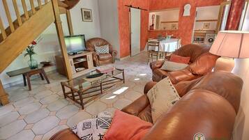 Una sala de estar con un sofá, una mesa de centro, un televisor y una escalera.