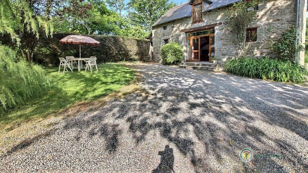 A stone building with a gravel driveway, a wooden table and chairs under a red umbrella, and a stone wall with climbing plants. - Poppies - SAINT GILDAS (ST GILDAS)