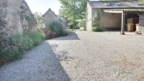 A gravel driveway leading to a rustic building with a sloped roof and a covered porch area. - Poppies - SAINT GILDAS (ST GILDAS)