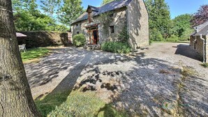 A stone building with a wooden door and a small porch, surrounded by trees and a gravel driveway. - Poppies - SAINT GILDAS (ST GILDAS)