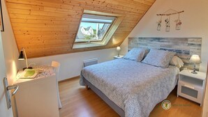 A bedroom with a sloped ceiling, a skylight, a bed with patterned bedding, bedside tables with lamps, and a small desk with a lamp. - Ty Kaol - PERROS GUIREC (PERROS GUIREC)