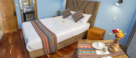 Un dormitorio con cama, mesita de noche y una pequeña mesa con un jarrón de flores.