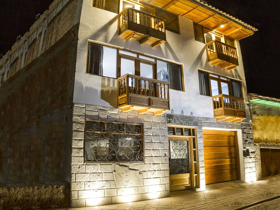 Un edificio de dos pisos con fachada de piedra, varios balcones con barandillas de madera y una entrada de garage.