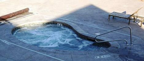 Ein Whirlpool mit Metallleiter, Holzliege und Metallbank.