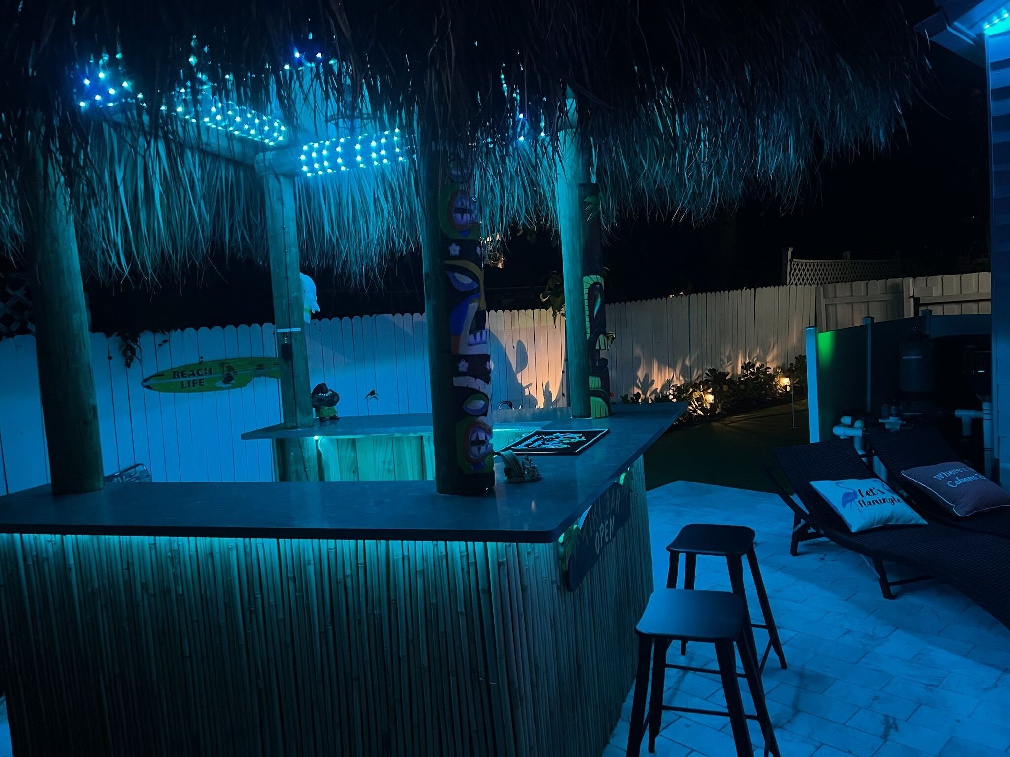 Un espace bar extérieur agrémenté d’un décor en bambou, d’une table de billard et de sièges confortables.