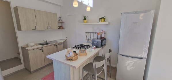 A compact kitchen with a central island, a refrigerator, and a microwave. - Villa The Dunes Cocus (Sicilia)