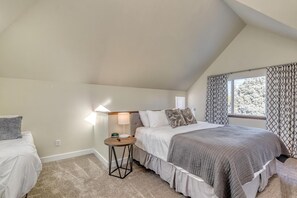 Une chambre à coucher avec un lit, une table de chevet, une lampe et une fenêtre avec des rideaux.