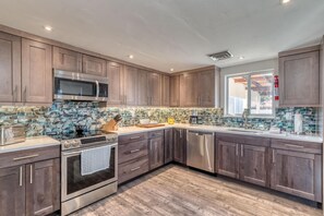 Eine moderne Küche mit dunklen Holzschränken, Edelstahlgeräten und einer gefliesten Spritzschutzwand.