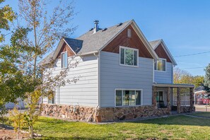Une maison à deux étages, avec des fondations en pierre, un porche couvert et une cheminée.
