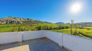A balcony with a view of a green landscape and mountains. - Huerta Nueva Cuevas del Becerro by Ruralidays (Málaga)