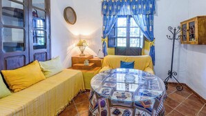 A room with two beds, a round table, a lamp, and a window with curtains. - Huerta Nueva Cuevas del Becerro by Ruralidays (Málaga)