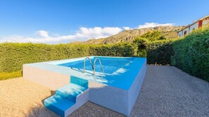 A rectangular swimming pool with steps leading into it, surrounded by a gravel area and lush greenery. - Huerta Nueva Cuevas del Becerro by Ruralidays (Málaga)