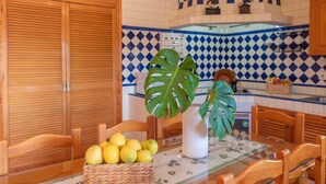 A kitchen with wooden cabinets, a tiled backsplash, and a dining table with chairs.