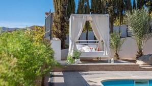 A private outdoor seating area with a canopy, a pool, and a view of the surrounding landscape.