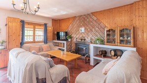 A cozy living room with a fireplace, wooden walls, and comfortable seating.