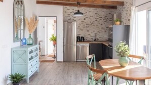 A modern kitchen with a stainless steel refrigerator, a dishwasher, and a dining area with a wooden table and chairs. - Casa Flamenquita Nerja by Ruralidays (Málaga)