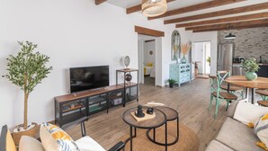 A modern living room with a TV, wooden flooring, and a dining area with a table and chairs. - Casa Flamenquita Nerja by Ruralidays (Málaga)