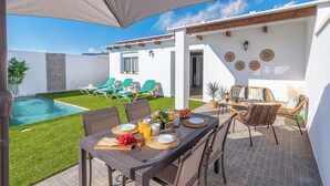 A patio with a dining table set for breakfast, a pool, and lounge chairs. - Casa Flamenquita Nerja by Ruralidays (Málaga)