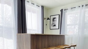 A room with a wooden bar counter and three bar stools. - The Club House - Suite 101 (Sault Ste. Marie)