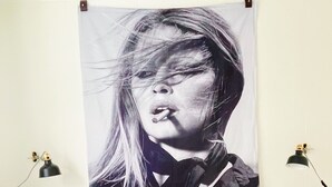 Ein Schlafzimmer mit einem Bett, einem gemusterten Kissen, einem großen schwarz-weißen Poster an der Wand und zwei Nachttischlampen.