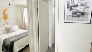 Une chambre d’hôtel avec un lit, une salle de bain avec un rideau de douche et un couloir menant à une autre pièce.