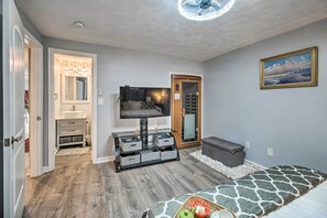 A bedroom with a bed, a TV, a storage unit, and a door leading to a bathroom.