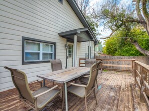 A wooden deck with a table and chairs, a covered area, and a view of a house with a window and a door. - Charming home near Fairgrounds & DownTown sleeps 9 (Oklahoma City)