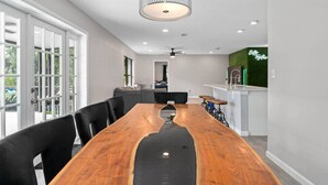 Una cocina moderna con una mesa de comedor de madera, sillas negras y una lámpara colgante.