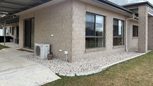 A modern building with a brick facade, large windows, and an air conditioning unit. - Spacious Country Home (Mount Tully)