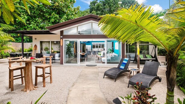 A modern house with a glass door leading to a patio area. - Surf, Relax and Explore the best of Avellanas (Playa Avellanas)