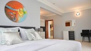 Ett modernt hotellrum med en stor säng, en tavla på väggen, ett skrivbord och en stol.