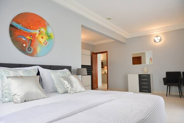Une chambre d’hôtel moderne avec un grand lit, un tableau au mur, un bureau et une chaise.