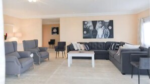 A modern living room with a sectional sofa, two armchairs, a coffee table, and a painting on the wall. - Atlantic Luxury Apartments (Penthouse) (cape point)