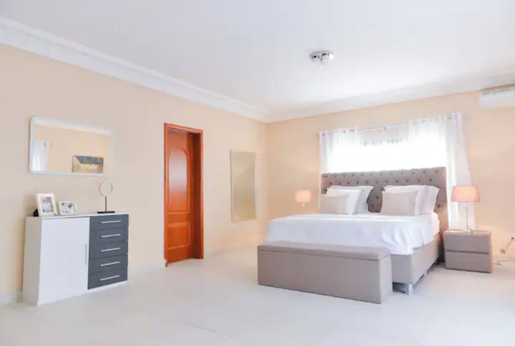 Ein Schlafzimmer mit einem Bett, Nachttischen, einem Schminktisch und einer Tür.