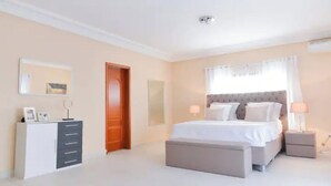 A bedroom with a bed, bedside tables, a dresser, and a door. - Atlantic Luxury Apartments (Penthouse) (cape point)