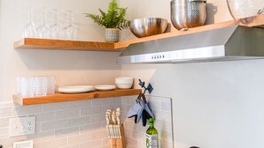 A kitchen with wooden shelves holding glassware, a plant, and kitchen utensils. - Coeur d'Alene Lake House - Hot Tub with lake view, beach/lake access/boat launch (Worley)