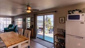 A cozy kitchen with a wooden table, chairs, a ceiling fan, and a view of a lake through large sliding glass doors. - Coeur d'Alene Lake House - Hot Tub with lake view, beach/lake access/boat launch (Worley)
