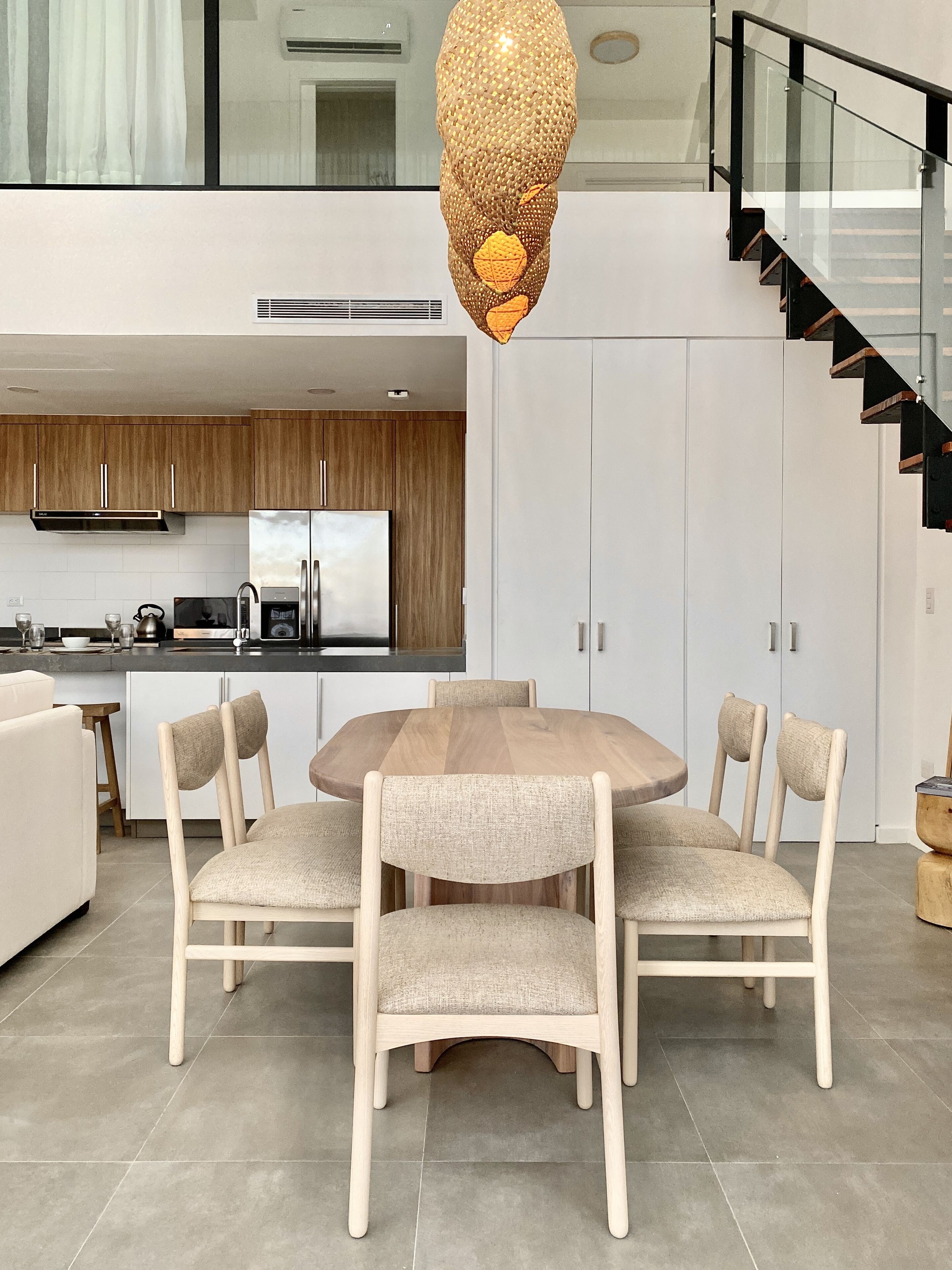 A modern kitchen with wooden cabinets, a stainless steel refrigerator, and a dining area with a round table and four chairs.